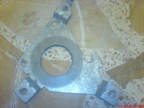 1992 Ford Crown Victoria - A metal bracket with a large central circular cutout and several smaller mounting holes is shown against a patterned background.