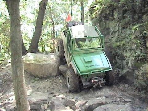 1992 Ford Bronco - Off-road vehicle tackling a challenging rocky path in a wooded area.