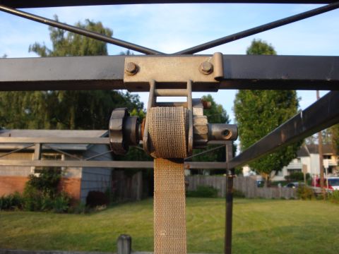 1988 Ford F-350 - Close-up of a ratchet strap mechanism against a backyard scene.