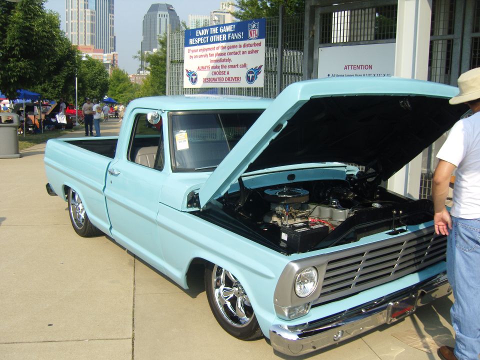 Light blue 1967 Ford F-100 pickup truck with hood open, chrome wheels, and custom grille