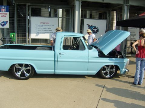 2007 Ford Mustang - A light blue 1967 Ford F-100 pickup truck is displayed with its hood open, the engine bay.