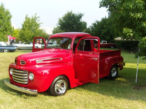 2007 Ford Mustang - Classic red Ford pickup truck displayed outdoors with its doors open, other vehicles in the background.