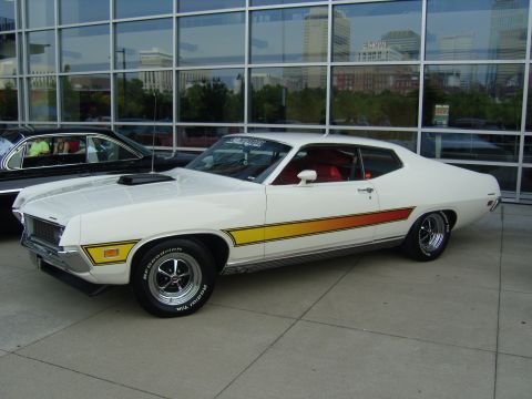 2007 Ford Mustang - A white 1970 Ford Torino GT is parked in front of a modern building with reflective windows.