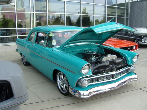 2007 Ford Mustang - A turquoise 1955 Ford Fairlane Crown Victoria is displayed with its hood open, parked next to other vehicles.