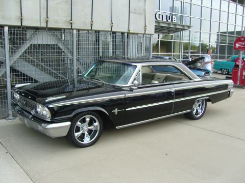 2007 Ford Mustang - A classic black 1963 Ford Galaxie 500 coupe is displayed outside a building with other vehicles in the background.
