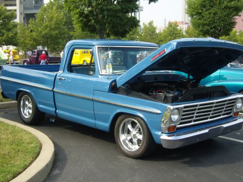 2007 Ford Mustang - A blue 1967 Ford F-100 pickup truck is parked with its hood open at an outdoor car show.