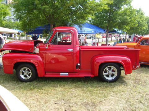 2007 Ford Mustang - Side view of a classic red pickup truck at an outdoor car show.