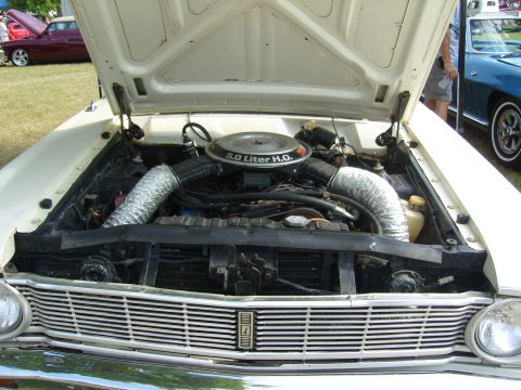 2007 Ford Mustang - The engine bay of a white car is open, revealing the engine and chrome grille.