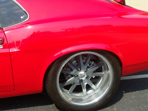 2007 Ford Mustang - Close-up of a red car's rear side with a custom wheel and visible brake system.