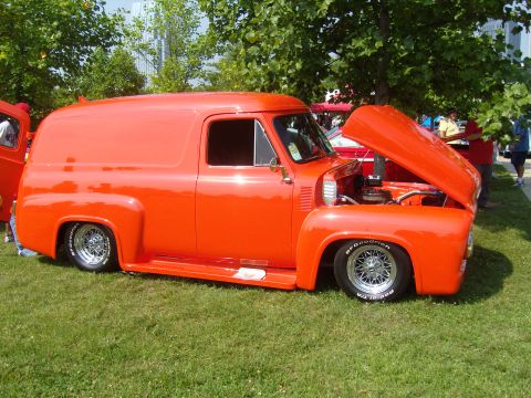 2007 Ford Mustang - A vintage orange panel van with its hood up sits on a grassy lawn.