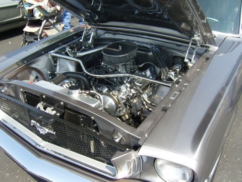 2007 Ford Mustang - The engine bay of a classic Ford Mustang is meticulously detailed with chrome components and a prominent V8 engine.