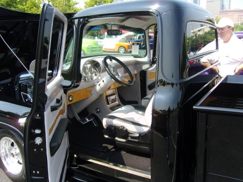 2007 Ford Mustang - A man looks into the customized interior of a black pickup truck at an outdoor event.