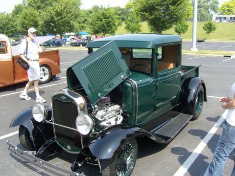 2007 Ford Mustang - A classic green pickup truck is displayed with its hood open at an outdoor event.