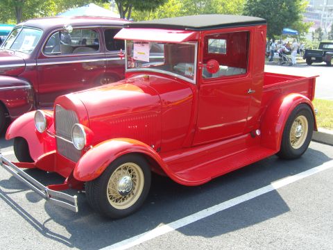 2007 Ford Mustang - A bright red vintage pickup truck is parked in a lot next to a darker colored sedan.
