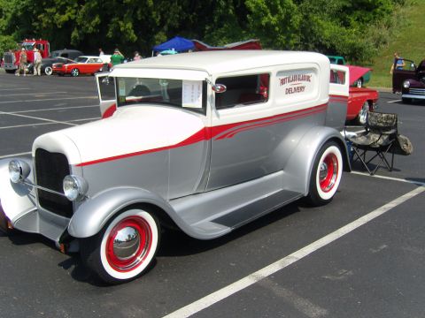 2007 Ford Mustang - A vintage delivery van is parked in a lot with other vehicles and people in the background.