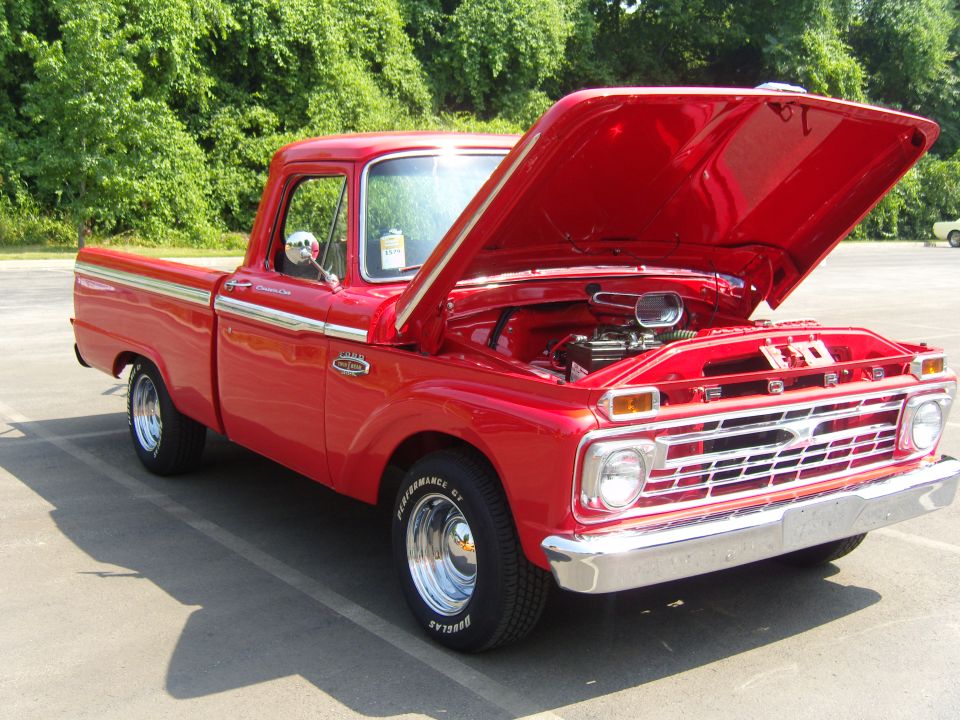 Red 1965 Ford pickup truck with hood open, showing the engine