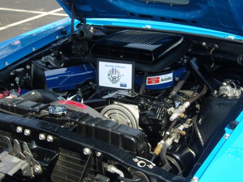 2007 Ford Mustang - The engine bay of a blue 1970 Ford Mustang is visible, a "Mustangs of Memphis" sign.