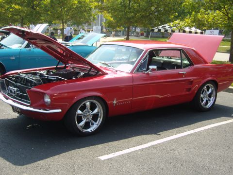 2007 Ford Mustang - A red 1967 Ford Mustang is displayed with its hood and trunk open, parked next to another vehicle.