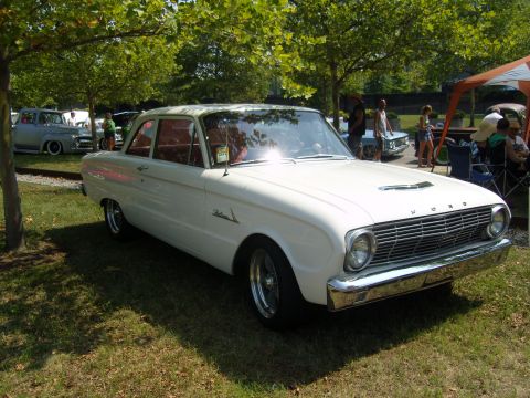 2007 Ford Mustang - A white 1960 Ford Falcon sedan is parked on grass under trees, with other vehicles visible in the background.