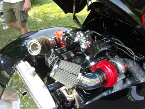 2007 Ford Mustang - The engine bay of a black car is visible, modified with twin turbochargers and custom intake piping.