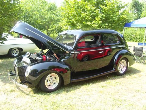 2007 Ford Mustang - A black hot rod sedan is displayed with its hood open, revealing the engine and custom components.