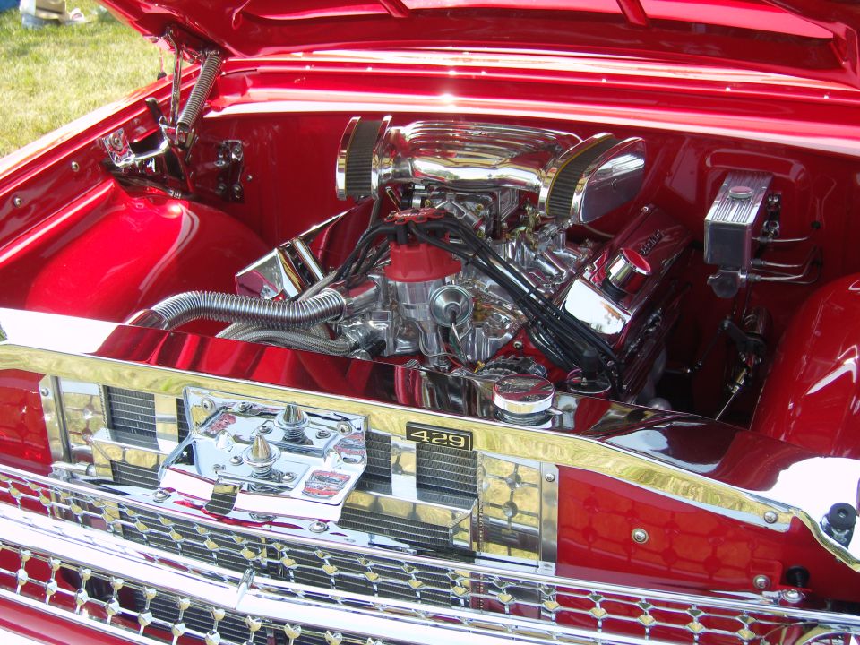 Shiny red engine bay with chrome V8 engine, air filters, and 429 badge