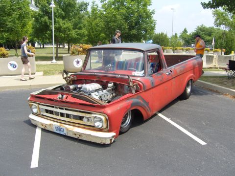 2007 Ford Mustang - This custom red pickup truck features an exposed engine and a colorful striped interior, parked at an outdoor event.