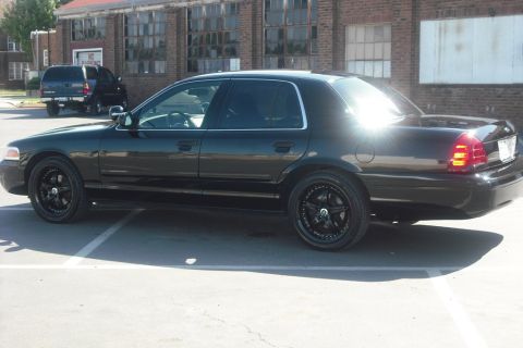 2003 Ford Crown Victoria - Side profile of a black 2003 Ford Crown Victoria with aftermarket wheels.