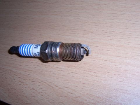 2007 Ford Mustang - A single spark plug is shown against a wooden background.