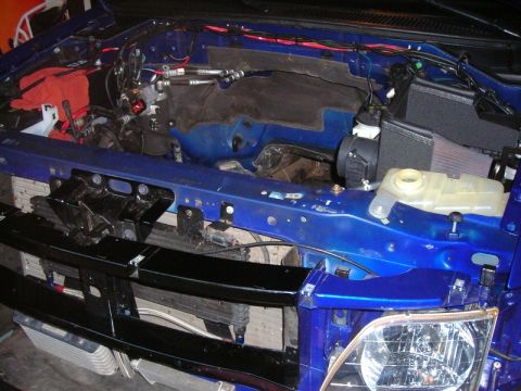 2007 Ford Mustang - Engine bay of a blue vehicle, showing various mechanical parts and wiring harnesses.
