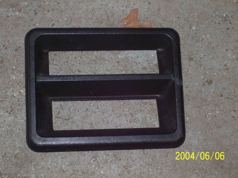 1990 Ford Bronco - A black plastic trim piece with two openings is shown against a concrete background.