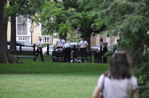 1996 Ford Bronco - Several officers are gathered around a bench in a park, attending to a person.