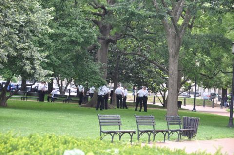 1996 Ford Bronco - A park scene shows several individuals in uniform gathered near benches and trees, with vehicles parked in the distance.