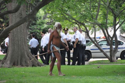 1996 Ford Bronco - Police officers observe a man walking with a stick in a park setting, with vehicles in the background.