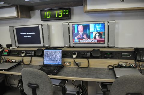 1996 Ford Bronco - Interior view of a mobile command center, multiple monitors displaying news and data, along with communication equipment.