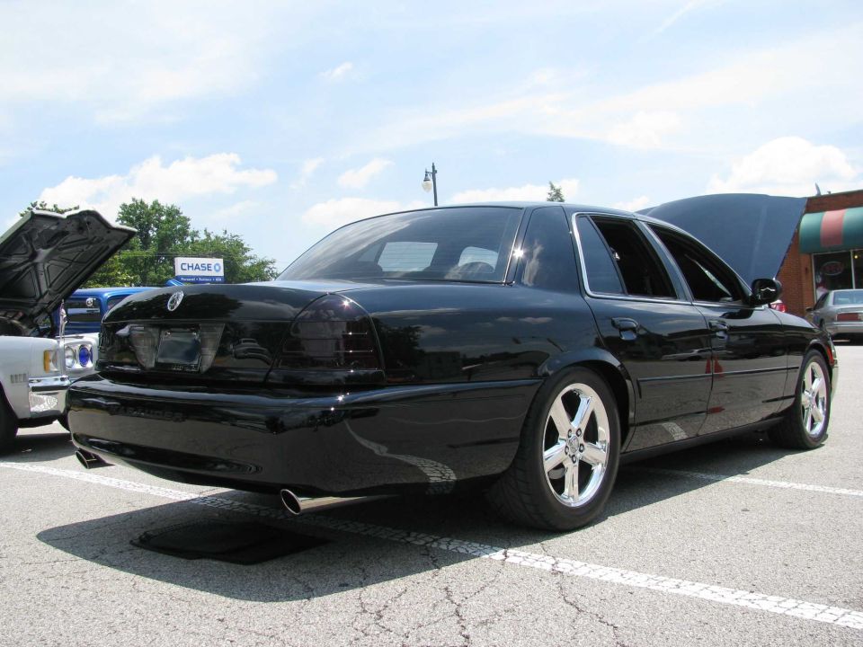 Black 2003 Mercury Marauder parked outside with hoods up on other cars