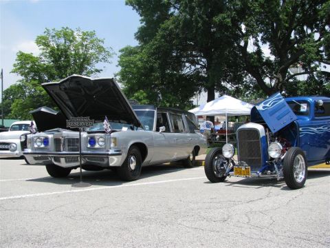 2003 Mercury Marauder - A silver hearse and a blue hot rod are parked side-by-side at an outdoor car show.