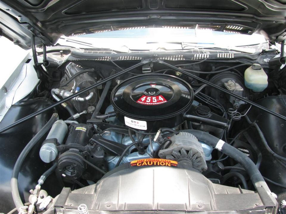 Engine bay with air cleaner labeled 455A High Performance. Caution sticker on fan shroud