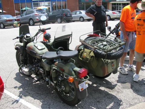 2003 Mercury Marauder - A motorcycle with a sidecar, painted in camouflage, is parked outdoors with people standing nearby.