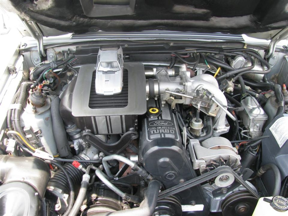 Ford engine bay with a silver toy car model on the intercooler cover. Text on engine reads 'Ford Fuel Injection Turbo'