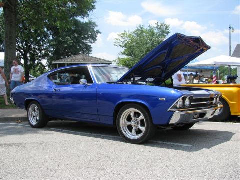 2003 Mercury Marauder - A blue 1969 coupe is displayed with its hood open at a car show, next to a yellow pickup truck.