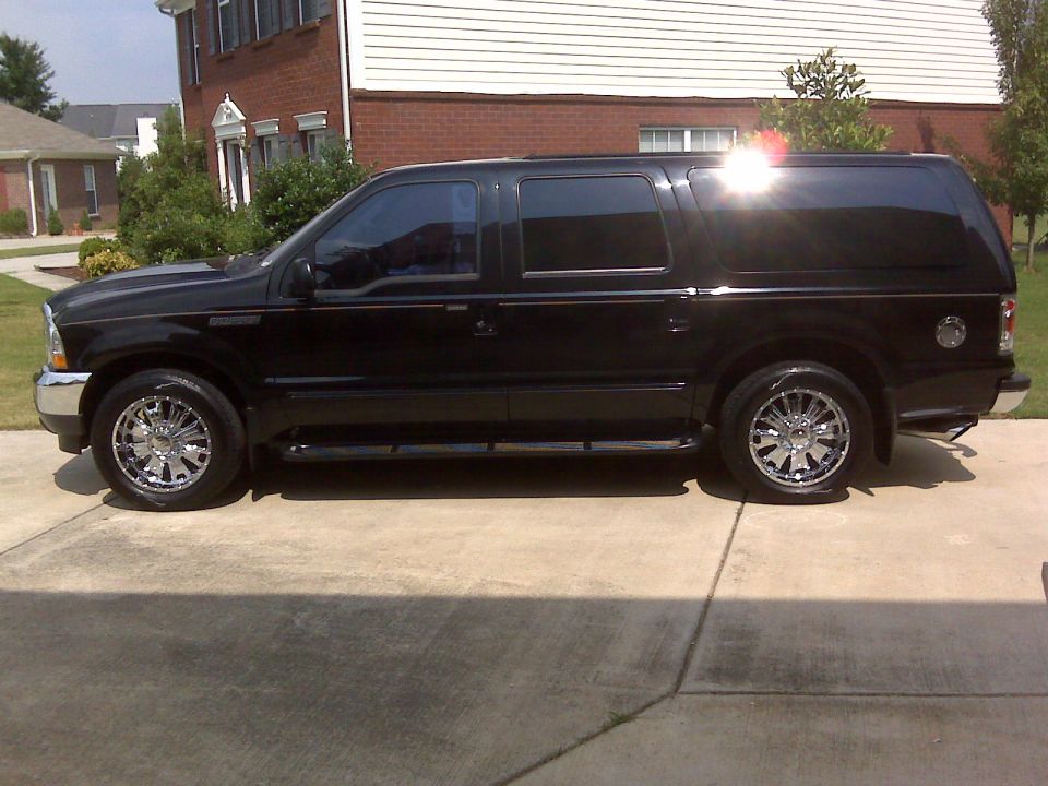 Side view of a black 2000 Ford Excursion with chrome wheels