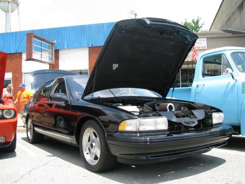 2003 Mercury Marauder - A black sedan, possibly from the 1990s, is displayed with its hood up at an outdoor car show.