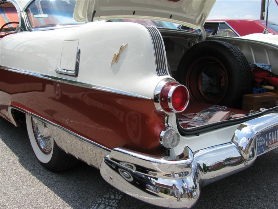 Rear view of a 1955 Pontiac Star Chief with trunk open, showing spare tire and chrome bumper