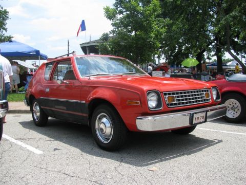 2003 Mercury Marauder - This red AMC Gremlin is parked next to another vehicle at an outdoor gathering.