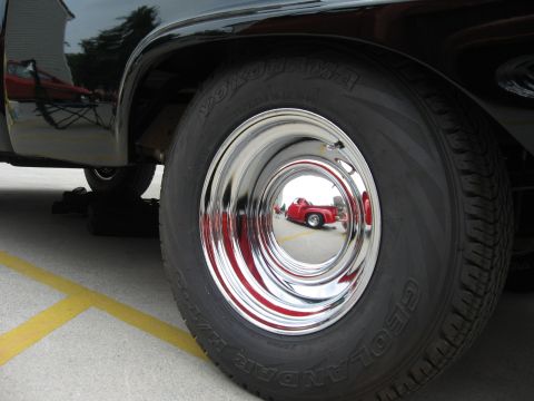 1966 Ford F-100 - Reflection of a red pickup truck in the chrome hubcap of a black pickup truck.