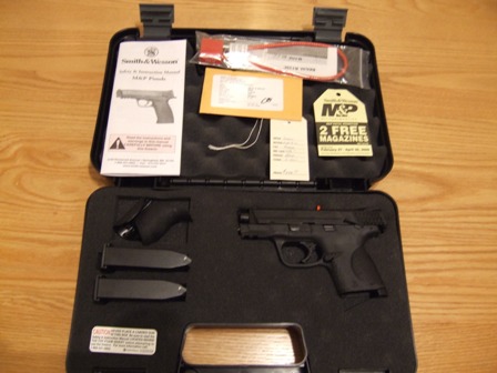 2002 Jeep TJ - A Smith & Wesson M&P pistol is displayed in its case with accessories, including extra magazines and a user manual.