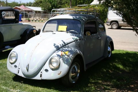 1984 Ford Bronco - A vintage Volkswagen Beetle with a roof rack sits on a grassy area, with another classic car visible to its left.