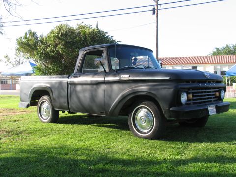 1984 Ford Bronco - This black Ford pickup truck is shown from a 3/4 front angle on a grassy lawn.