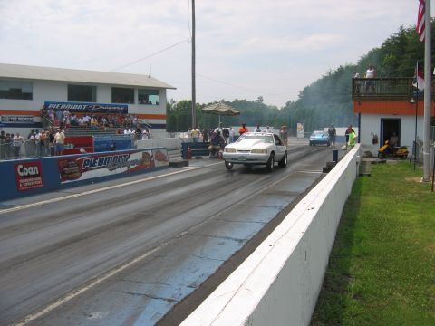 1992 Ford Mustang - A white 1992 Ford Mustang is on the drag strip, with another car in the distance and spectators watching from Piedmont Dragway.
